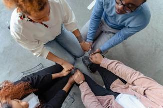 4 people sitting and holding hands