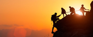 a group of people climbing a mountain at sunset